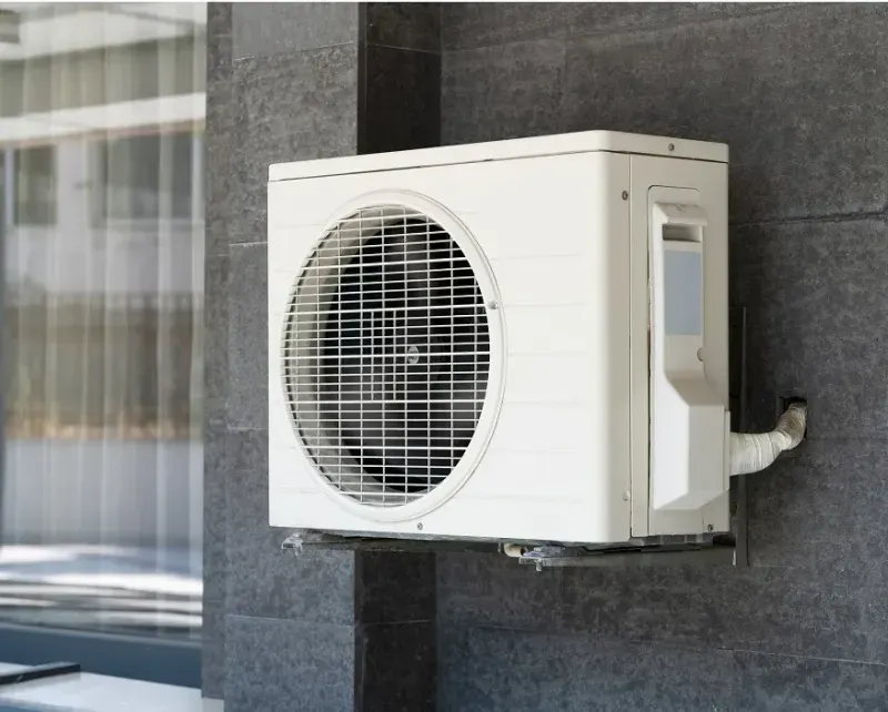 Wall-mounted ductless mini-split outdoor unit on a home exterior
